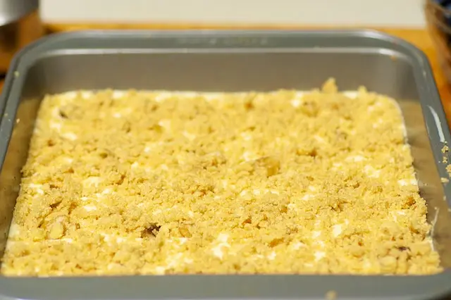 All the reserved the crumb mixture is evenly sprinkled over the creamy filling.