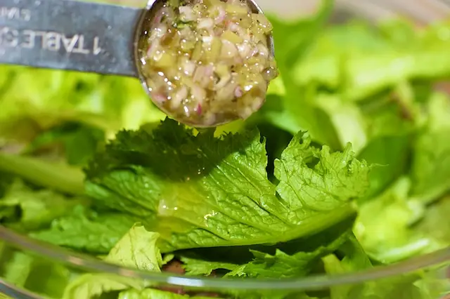 In a large bowl, add the mixed baby greens and 2 tablespoons of vinaigrette, toss until evenly coated.