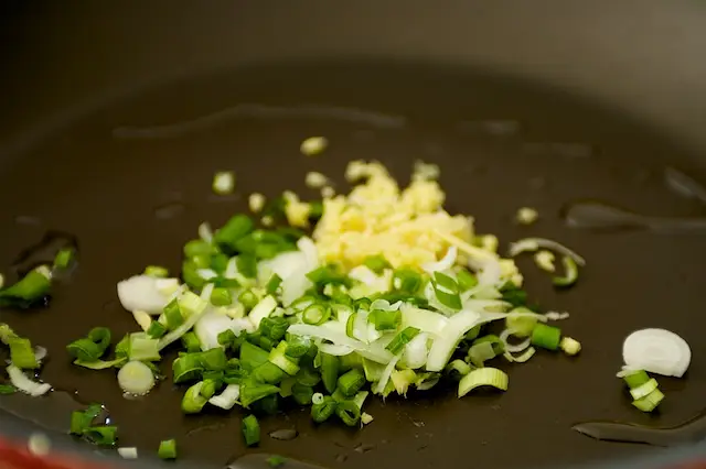 Heat 1 teaspoon of oil in a large nonstick skillet until hot. Add half of each scallions, gingers and garlic.