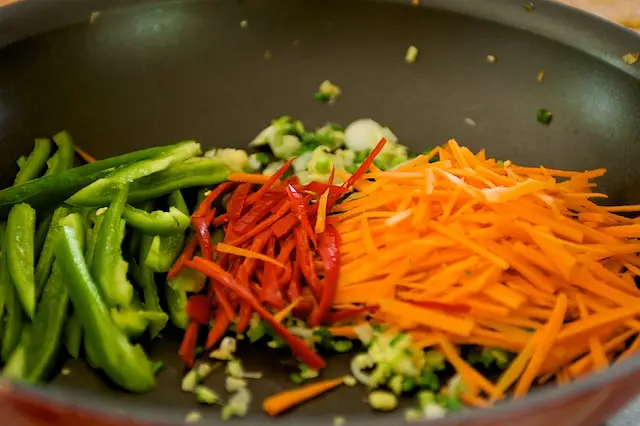 Stir in the carrots, red and green chili peppers.