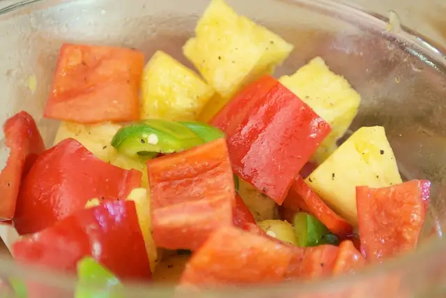Add the pineapple chunks and bell peppers, 1 ½ tablespoons of olive oil, salt and black pepper to taste in a medium bowl, toss until well coated.