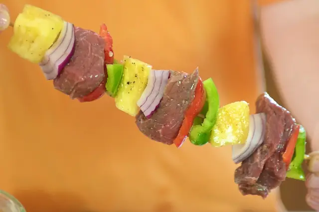 Thread each skewer with a pineapple chunk, three layers of onion (in one stack) and cube of beef.