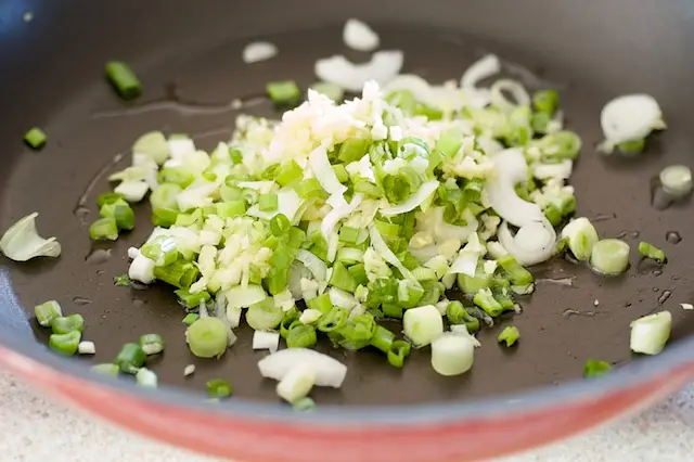 Heat the oil in a wok or nonstick skillet until hot, add the garlic, ginger and scallions.