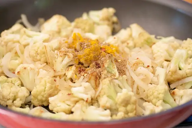 Add the spice mixture into partially cooked cauliflower and onion.