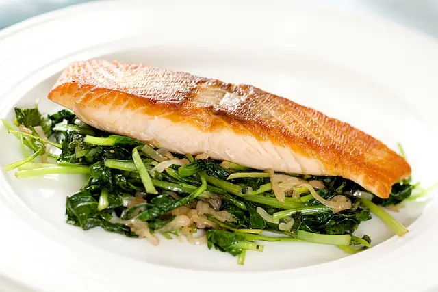 Divide the cooked baby spinach or tatsoi evenly among 4 serving plates. 