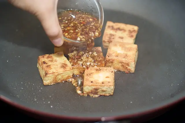 Reduce the heat to low, pour half of the sauce into the pan,