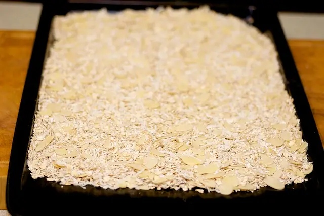 Place the oats, coconut, and almonds on a baking sheet, mix well and spread evenly. 