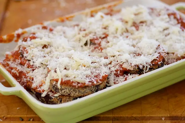 Lay another layer of eggplant slices, tomato sauce and two cheeses, repeat until all the ingredients have been used up. 