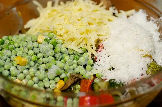 Then in a large bowl, add the roasted vegetables, cheeses, peas, salt and black pepper to taste.