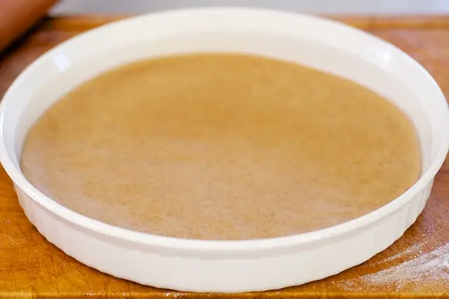 Place the dough into a 10-inch quiche dish or cake pan greased with butter. 