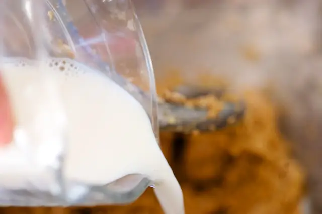 With the machine running, add the hot skim milk. 