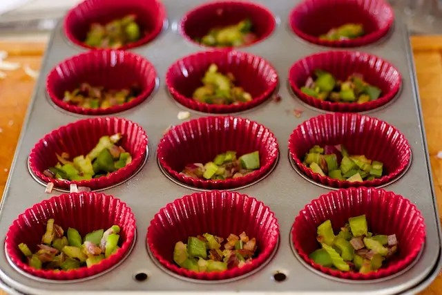 Evenly distribute among the 12 cups of tin the sauteed vegetables,