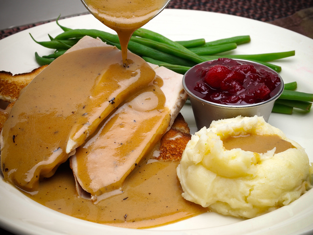 Smooth lump-free gravy pouring over turkey and mashed potatoes