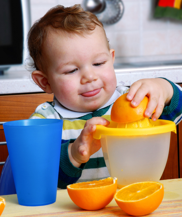 child concentrating on making orange juice